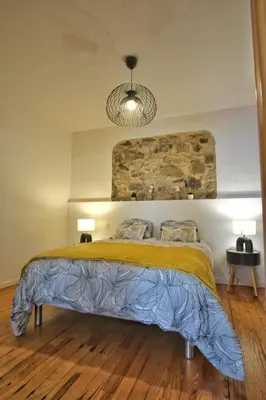 a bedroom with a bed with a stone wall at Loft de caractère centre-ville in Narbonne