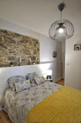 a bedroom with a large bed with a stone wall at Loft de caractère centre-ville in Narbonne