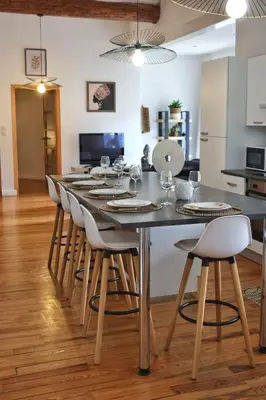 a dining room with a table with chairs and a kitchen at Loft de caractère centre-ville in Narbonne