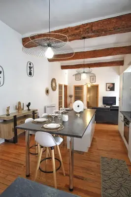 a kitchen and living room with a table and chairs at Loft de caractère centre-ville in Narbonne