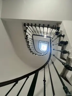 a spiral staircase in a building with a blue light at L'Ébène - Wifi - Proche des Halles et du centre ville in Narbonne