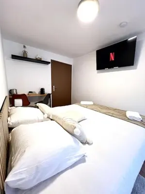 two beds in a hotel room with a tv on the wall at Les chambres de la bastide - 303 in Carcassonne