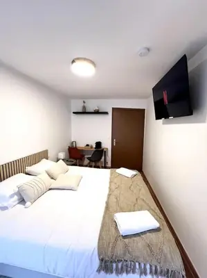 a bedroom with a large white bed with a flat screen tv at Les chambres de la bastide - 303 in Carcassonne