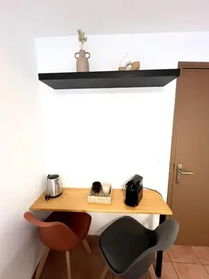 a wooden table with two chairs next to a wall at Les chambres de la bastide - 303 in Carcassonne