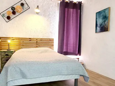 a bedroom with a bed and a purple curtain at Le Marceau Terrasse Sur Le Toit in Narbonne