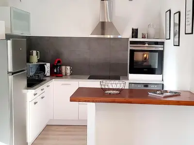a kitchen with white cabinets and a wooden counter top at Le Marceau Terrasse Sur Le Toit in Narbonne
