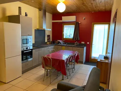 a kitchen with a table and a white refrigerator at Appartement T2 spacieux in Trévillach