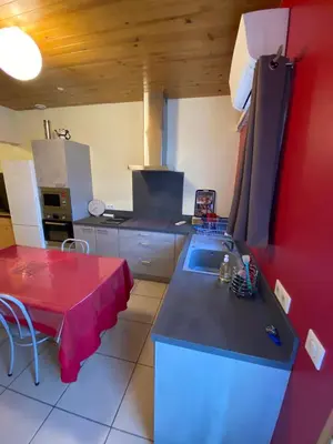 a kitchen with a sink and a red table in it at Appartement T2 spacieux in Trévillach