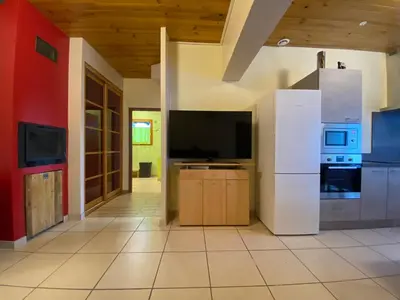 a living room with a tv and a white refrigerator at Appartement T2 spacieux in Trévillach