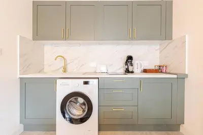 a kitchen with a washing machine under a counter at Le Cosy Bernard , Parking, Piscine, Netflix in Carcassonne