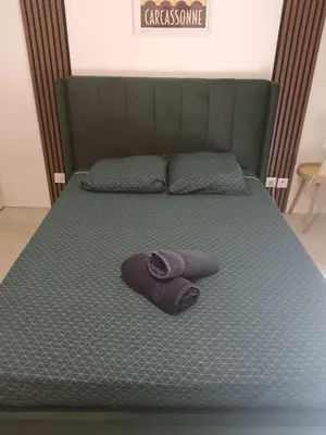 a bed with a purple towel laying on it at Le Cosy Bernard , Parking, Piscine, Netflix in Carcassonne