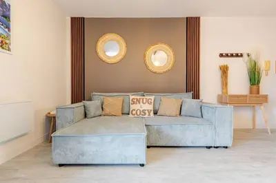 a living room with a blue couch and two mirrors at Le Cosy Bernard , Parking, Piscine, Netflix in Carcassonne