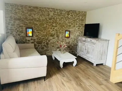 a living room with a couch and a tv and a table at Charmante Maison l Jardin l Clim in Carbes