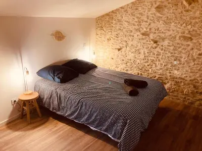 a bedroom with a bed and a brick wall at Charmante Maison l Jardin l Clim in Carbes