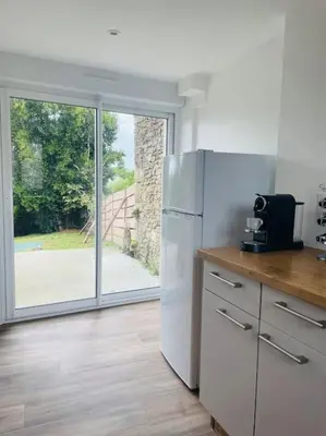 a kitchen with a refrigerator and a sliding glass door at Charmante Maison l Jardin l Clim in Carbes
