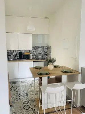 a kitchen with a wooden table and white cabinets at Le Borel I in Castres
