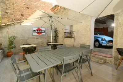 a table and chairs with an umbrella and a car at B&B Hugo Puisserguier in Puisserguier