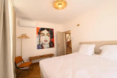 a bedroom with a white bed and a painting on the wall at B&B Hugo Puisserguier in Puisserguier