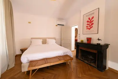 a bedroom with a white bed and a fireplace at B&B Hugo Puisserguier in Puisserguier