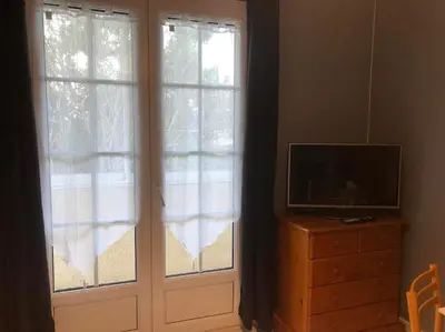 a living room with two windows and a television at Chez Sophie et Bernard in Saverdun