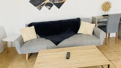 a living room with a couch with a remote control at Maison T3 avec jardin in Narbonne