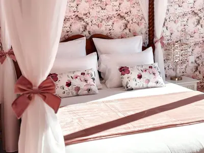 a bedroom with a white bed with pink flowers at LV House & Gardens in Carcassonne
