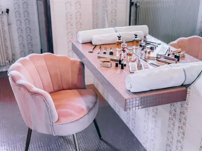 a dressing table with a pink chair and cosmetics at LV House & Gardens in Carcassonne