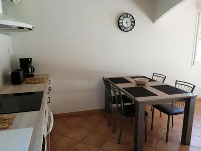 a kitchen with a table with chairs and a clock on the wall at GITE CHEZ JULES ET ODETTE in Comigne