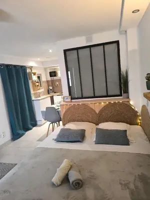 a bedroom with a large bed with a large window at agréable studio in Narbonne