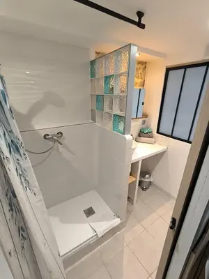 a white bathroom with a shower and a sink at agréable studio in Narbonne