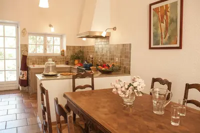 a kitchen with a wooden table with flowers on it at Château de la Motte - Entre Narbonne et le Canal du Midi in Marcorignan