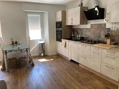 a kitchen with white cabinets and a table in it at La tranquillité en centre-ville avec terrasse in Limoux