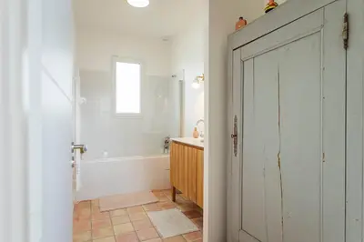 a bathroom with a white door and a tub and a sink at Maison charme et confort - piscine chauffée in Tarabel