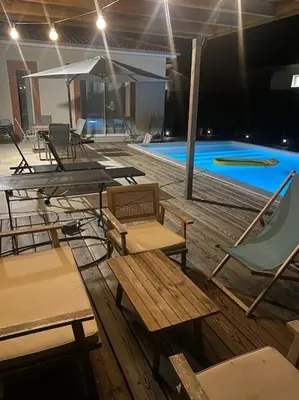a pool with tables and chairs next to a swimming pool at Maison charme et confort - piscine chauffée in Tarabel