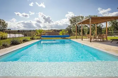 a large swimming pool with a gazebo at Maison charme et confort - piscine chauffée in Tarabel
