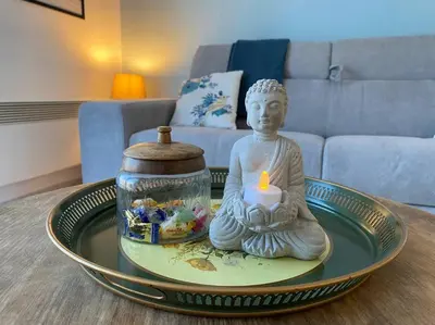 a statue of a buddha sitting on a table with a candle at Le Voyage Bleu, Clim Parking in Carcassonne