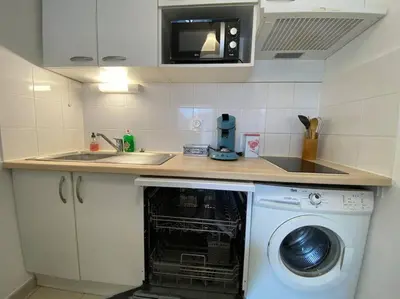 a kitchen with a dishwasher under a counter with a sink at Le Voyage Bleu, Clim Parking in Carcassonne