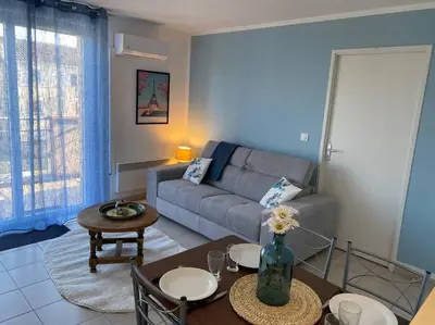 a living room with a couch and a table at Le Voyage Bleu, Clim Parking in Carcassonne