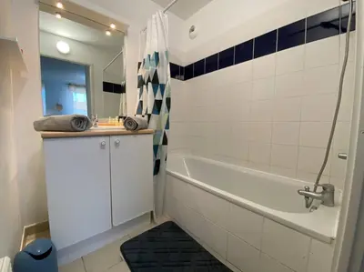 a bathroom with a tub and a sink and a mirror at Le Voyage Bleu, Clim Parking in Carcassonne
