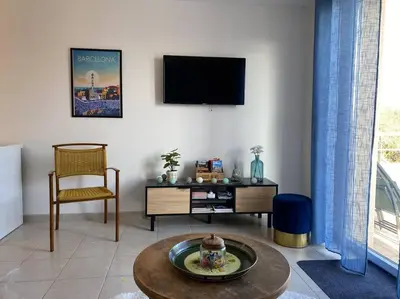 a living room with a tv and a table and a chair at Le Voyage Bleu, Clim Parking in Carcassonne