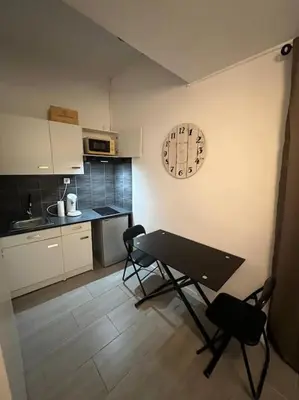 a kitchen with a table and chairs and a clock on the wall at Studio Distillerie in Narbonne