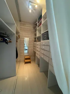 a walk in closet with white cabinets and a chair at la vue des étangs in Bages