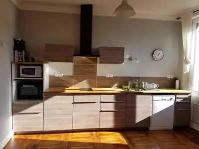 a kitchen with wooden cabinets and a clock on the wall at T2 Gautier proche Cité Médiévale parking privé in Carcassonne