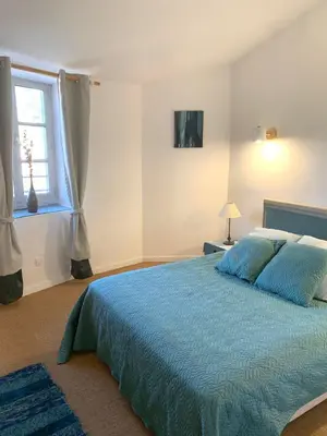 a bedroom with a blue bed and a window at Nichoir des gorges in Montolieu