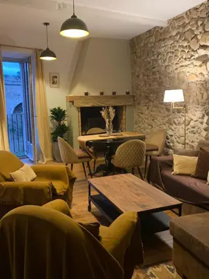 a living room with a table and a stone wall at Nichoir des gorges in Montolieu