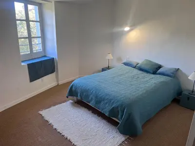 a bedroom with a blue bed and a window at Nichoir des gorges in Montolieu