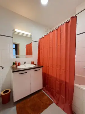 a bathroom with an orange shower curtain and a sink at La Cité Voltaire in Carcassonne