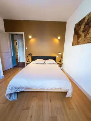 a bedroom with a large white bed and wooden floors at La Cité Voltaire in Carcassonne