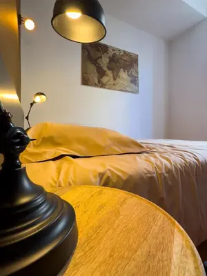 a room with a table and a bed and a lamp at La Cité Voltaire in Carcassonne