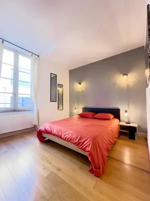 a bedroom with a bed with red sheets and a large window at La Cité Voltaire in Carcassonne